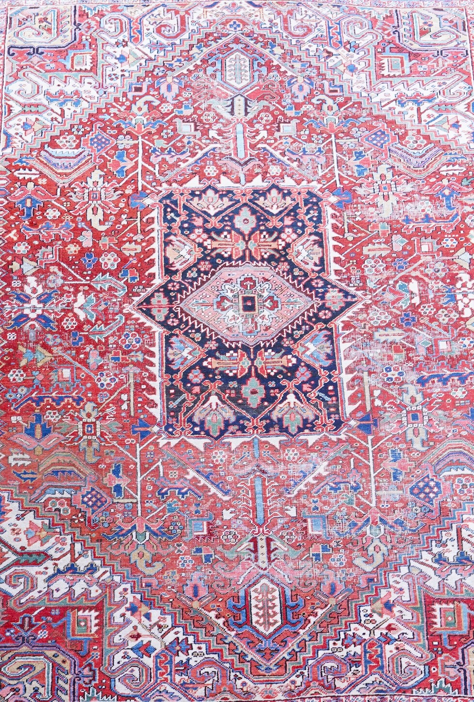An antique Heriz brick red ground carpet with central